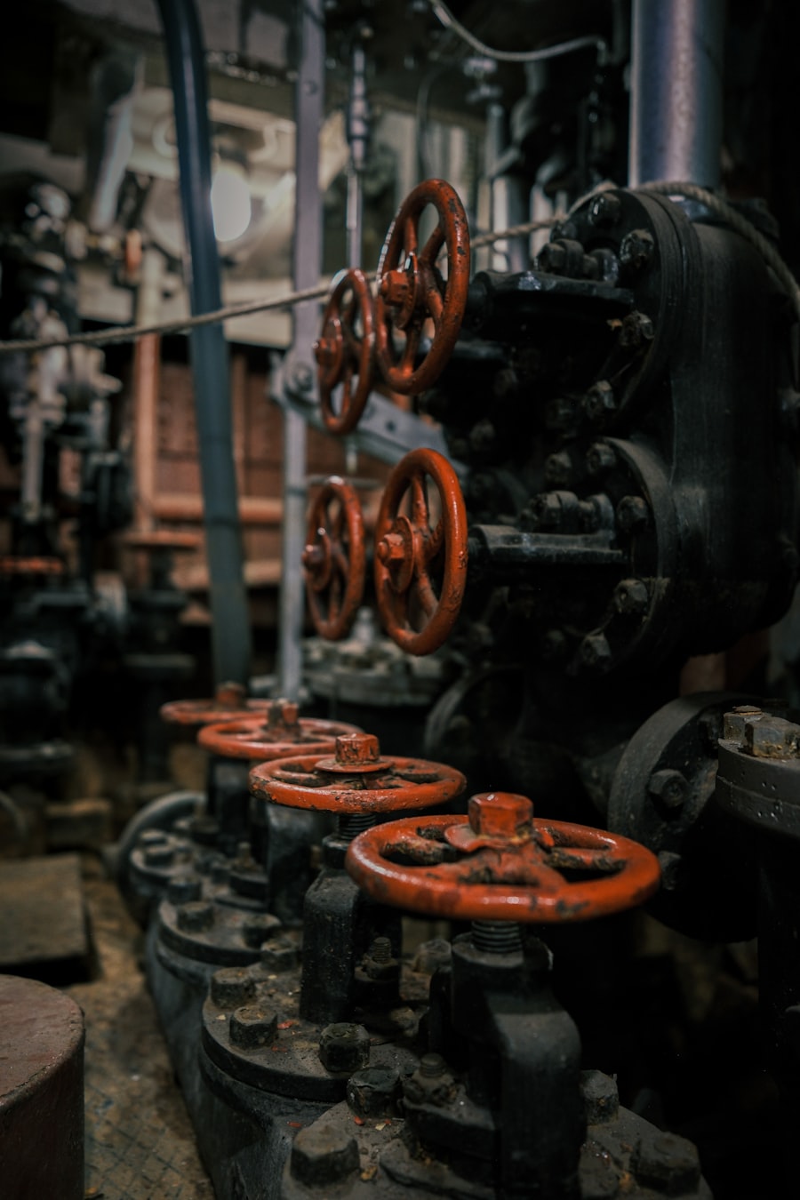 A row of industrial valves with red handwheels in a mechanical room