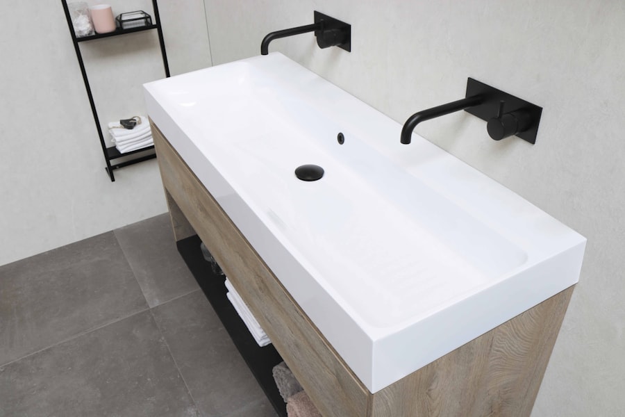 A modern bathroom vanity with a wide white sink and matte black wall-mounted faucets